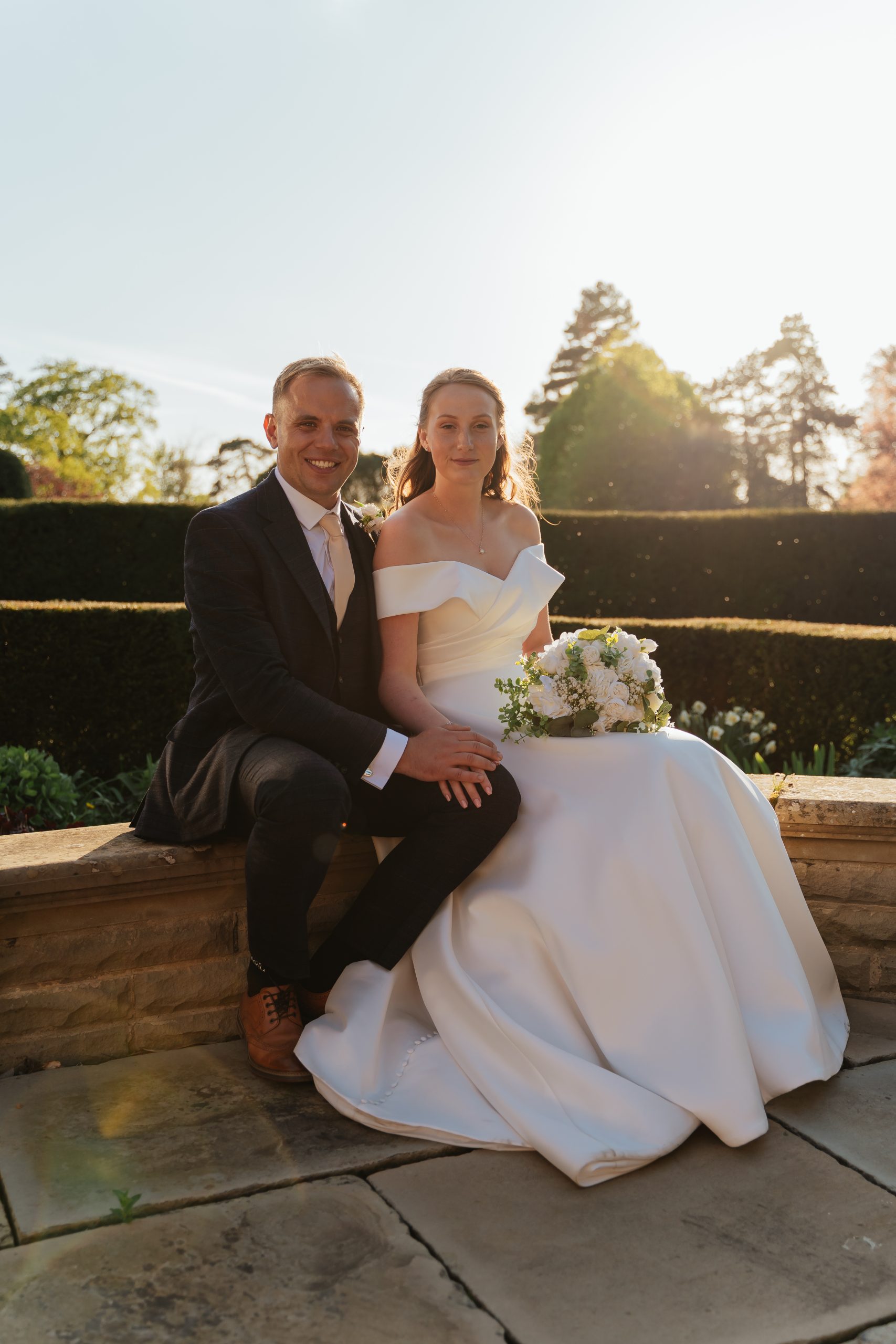 A couple snuggled up under a blossom tree at Fanhams Hall in Golden Hour